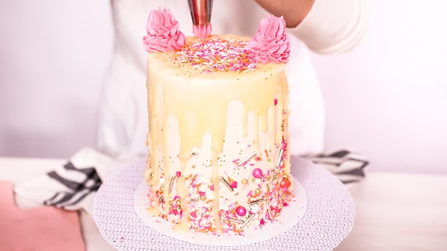 Pas à pas. Glaçage au beurre italien rose passepoilé sur un grand gâteau d'anniversaire.