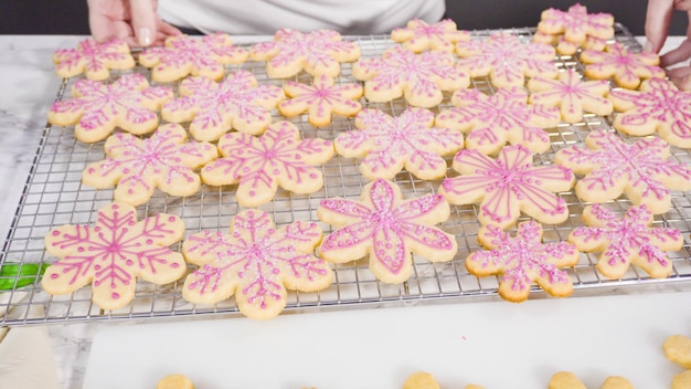 Pas à pas. Glaçage biscuits au sucre en forme de flocon de neige avec glaçage royal rose.