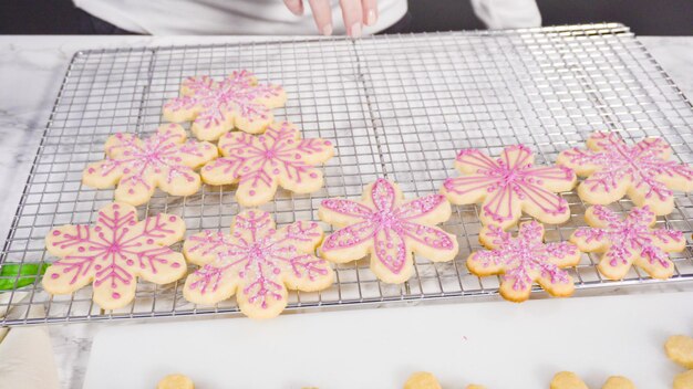 Pas à pas. Glaçage biscuits au sucre en forme de flocon de neige avec glaçage royal rose.