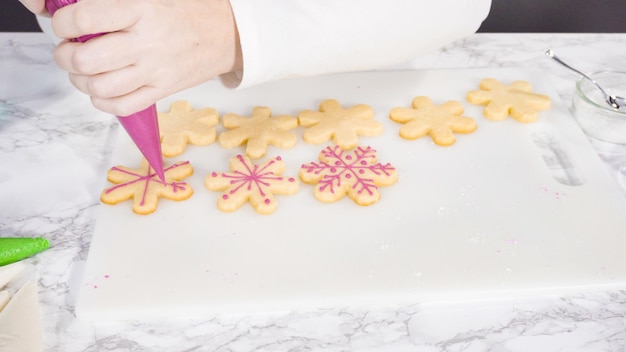 Pas à pas. Glaçage biscuits au sucre en forme de flocon de neige avec glaçage royal rose.