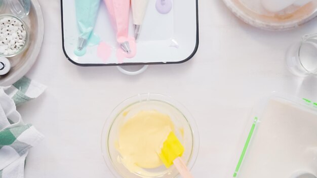 Pas à pas. Mélanger du colorant alimentaire dans du glaçage royal pour décorer des biscuits au sucre de licorne.