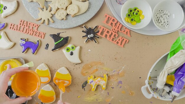 Pas à pas. Mère et fille décorant des biscuits au sucre d'Halloween avec un glaçage royal coloré.