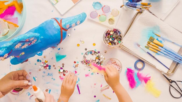 Pas à Pas. Mère Et Fille Décorant Ensemble Une Licorne En Papier Mâché.