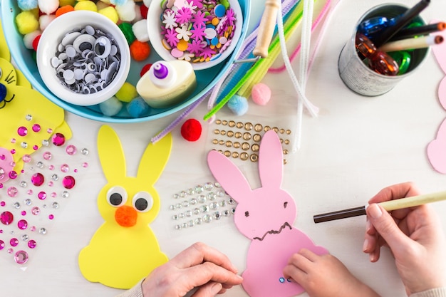 Pas à pas. Mère et fille décorant des lapins de Pâques.