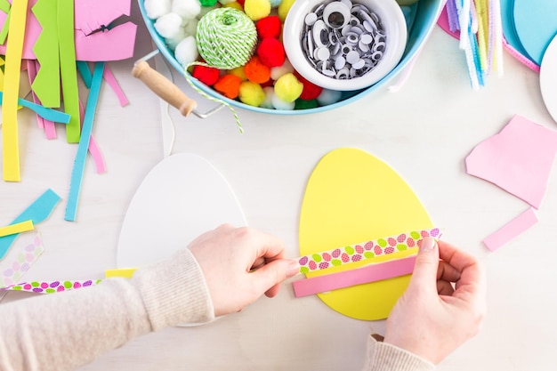 Pas à pas. Mère et fille décorant des oeufs de Pâques en papier.