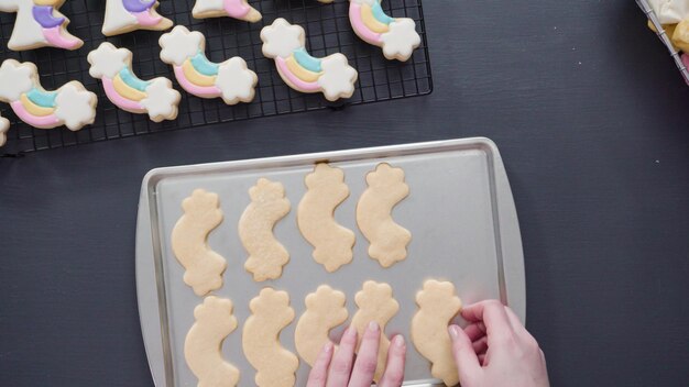 Pas à pas. Mise à plat. Décorer des biscuits au sucre de licorne avec du glaçage royal sur une plaque à pâtisserie.