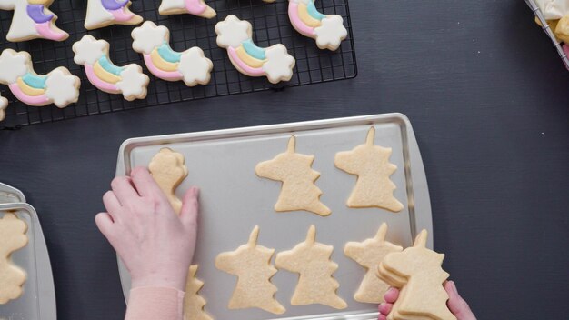 Pas à pas. Mise à plat. Décorer des biscuits au sucre de licorne avec du glaçage royal sur une plaque à pâtisserie.