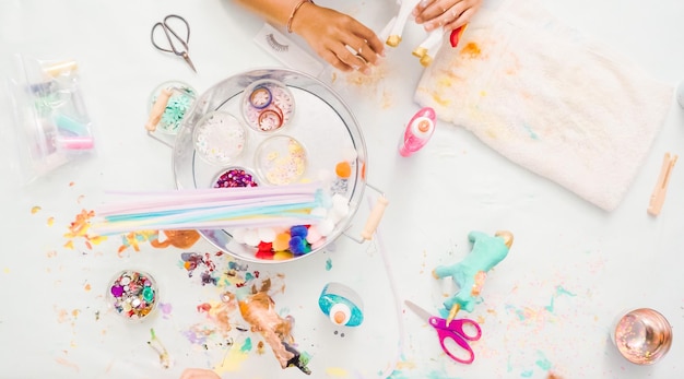 Pas à pas. Petites filles décorant une licorne en papier mâché avec des paillettes et des fleurs en papier.