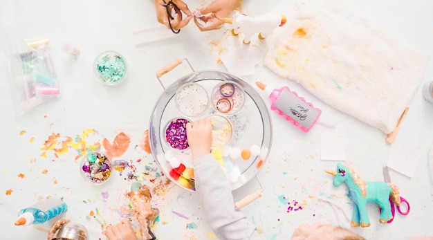 Pas à pas. Petites filles décorant une licorne en papier mâché avec des paillettes et des fleurs en papier.