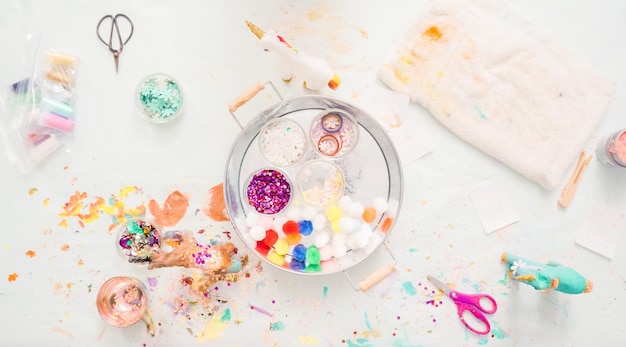 Pas à pas. Petites filles décorant une licorne en papier mâché avec des paillettes et des fleurs en papier.