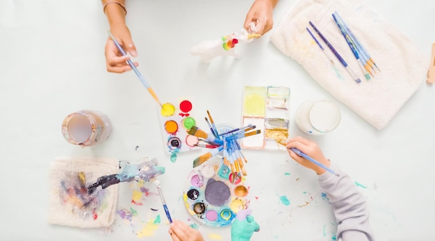 Photo pas à pas. petites filles peignant une licorne en papier mâché avec de la peinture acrylique.