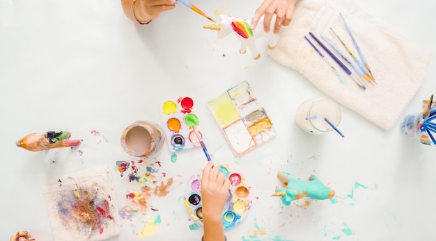 Pas à pas. Petites filles peignant une licorne en papier mâché avec de la peinture acrylique.