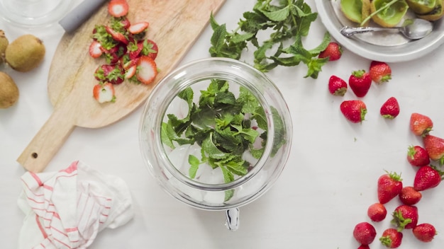 Pas à pas. Préparation de l'eau infusée biologique dans un distributeur de boissons en verre.