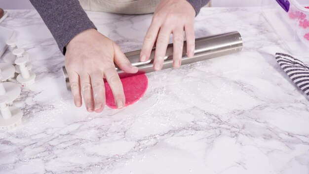 Pas à pas. Rouler notre fondant rose sur un comptoir en marbre.