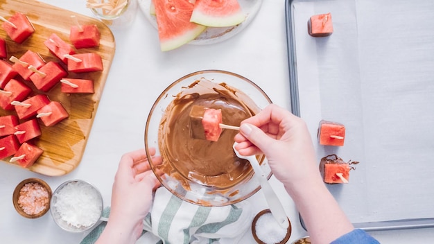 Pas à pas. Tremper les cubes de pastèque dans du chocolat fondu et garnir de sel de mer et d'amandes.