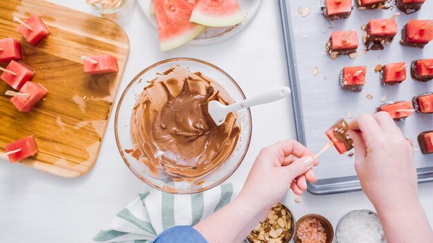 Pas à pas. Tremper les cubes de pastèque dans du chocolat fondu et garnir de sel de mer et d'amandes.