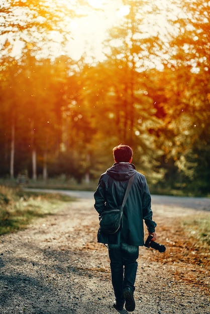 Pas de visage homme retour à la caméra trekking dans le parc d'automne avec son appareil photo Photographe amateur en plein air