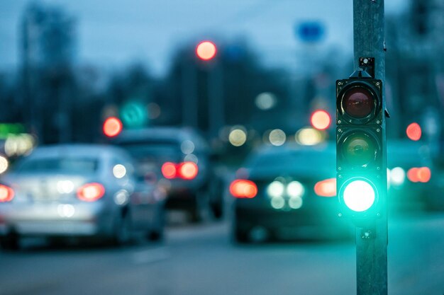 Un passage de ville avec un sémaphore sur un fond flou avec des voitures dans les rues du soir lumière verte