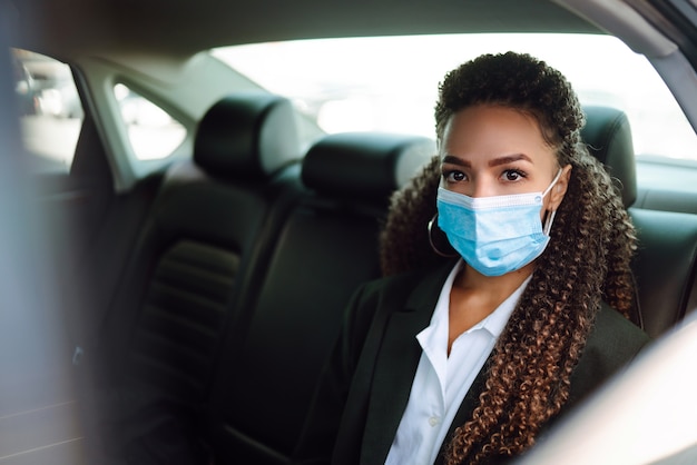 Passager détendue dans un masque médical de protection dans la voiture de taxi.