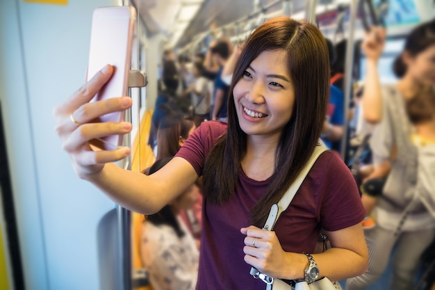 Passager de femme asiatique avec un costume décontracté prenant selfie par téléphone mobile