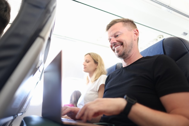 Passager de l'homme volant en avion et tapant sur le clavier d'un ordinateur portable