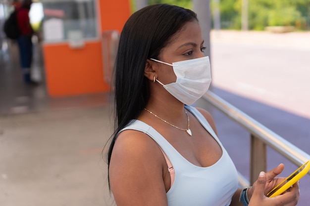 Passager portant un masque naviguant avec son téléphone portable dans une gare routière