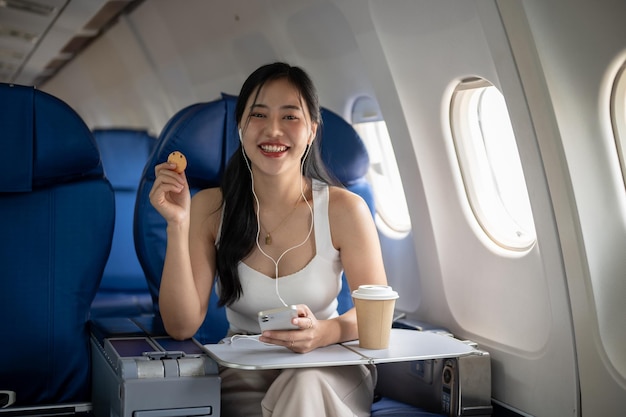 Une passagère apprécie des collations et écoute de la musique sur ses écouteurs pendant le vol.