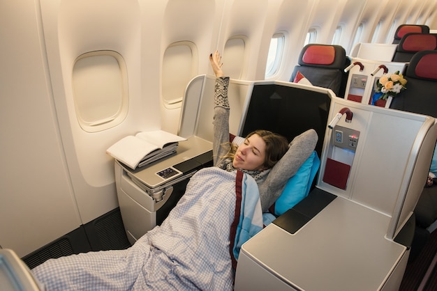 Passagère se détendre à la classe affaires de l'avion dans un siège unique confortable