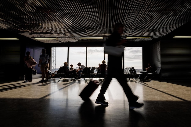 Passagers avec des bagages marchant le long d'une salle de départ de l'aéroport