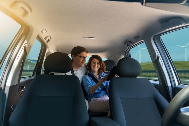 Les passagers s'assoient sur le siège arrière et regardent la tablette numérique pendant que la voiture autonome roule sur le h