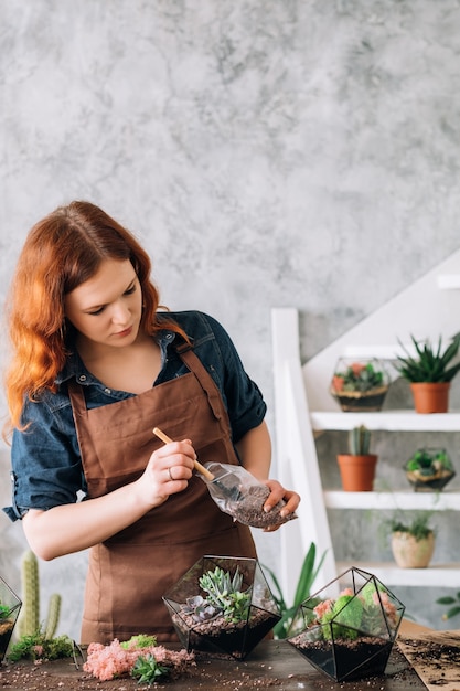 Passe-temps de culture de plantes. Femme travaillant sur un nouvel arrangement décoratif, utilisant des vases en verre et du gravier pour les succulentes.