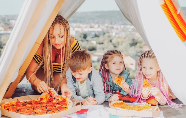 Passe-temps familial Mère avec enfants jouant ensemble Manger de la pizza Camping familial Maman avec enfants Concept de vacances d'été Fête des mères