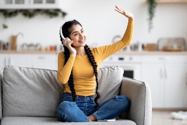 Passe-temps préféré joyeuse jeune femme indienne écoutant de la musique dans des écouteurs sans fil