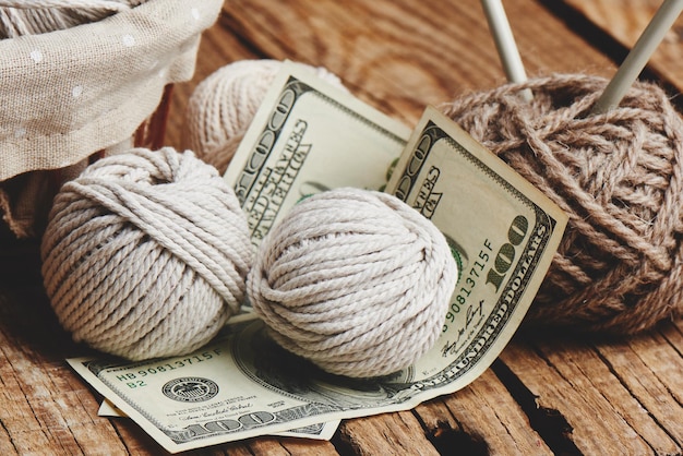 Passe-temps rentable. Gains sur la couture. Boules de fil de couleur naturelle, aiguilles à tricoter et argent sur une table en bois.