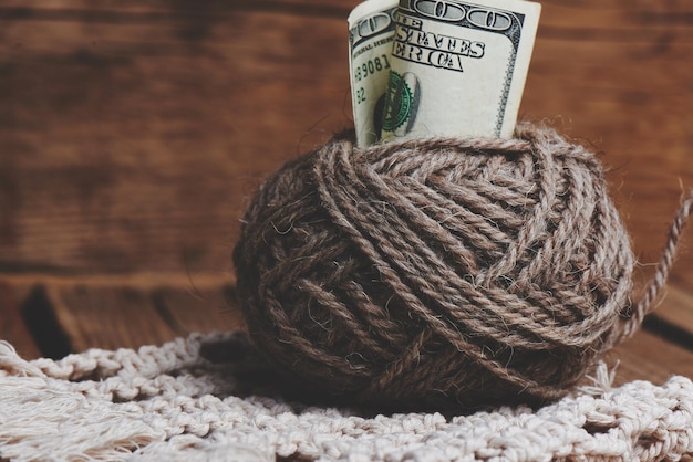 Passe-temps rentable. Gains sur la couture. Boules de fil de couleur naturelle, aiguilles à tricoter et argent sur une table en bois.