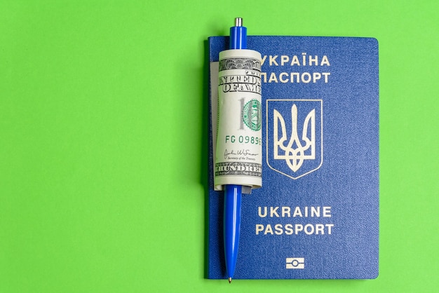 Passeport biométrique ukrainien avec un billet de cent dollars et un stylo