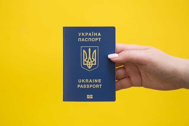 Passeport d'un citoyen d'Ukraine dans une main féminine sur un fond jaune