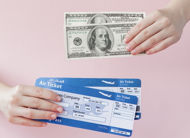 Passeport, dollars et billet d'avion en main de femme sur un rose