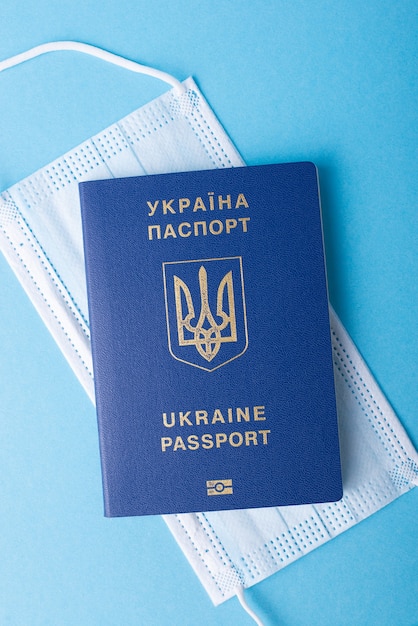 Passeport international du citoyen ukrainien sur un masque médical sur fond bleu