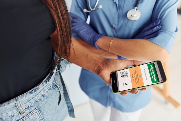 Avec passeport numérique Médecin en uniforme faisant la vaccination au patient