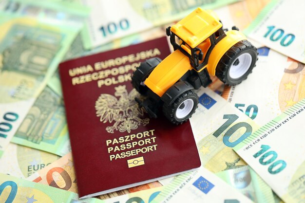 Photo passeport polonais rouge et tracteur jaune sur les billets en euros en gros plan