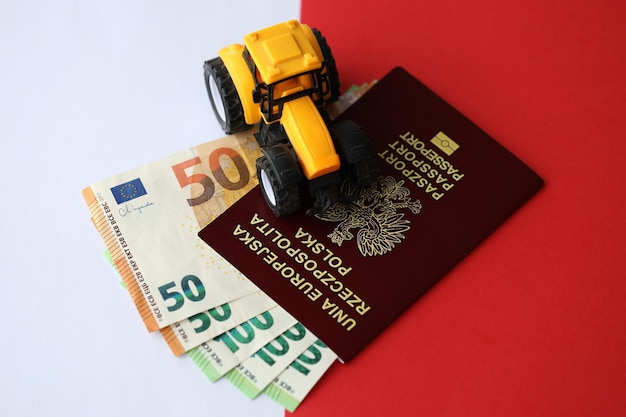 Photo passeport polonais rouge et tracteur jaune sur la monnaie euro et drapeau rouge et blanc lisse de la pologne