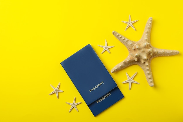 Passeports et étoiles de mer sur fond isolé jaune, vue du dessus