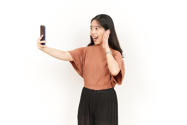 Passer un appel vidéo à l'aide d'un smartphone d'une belle femme asiatique isolée sur fond blanc
