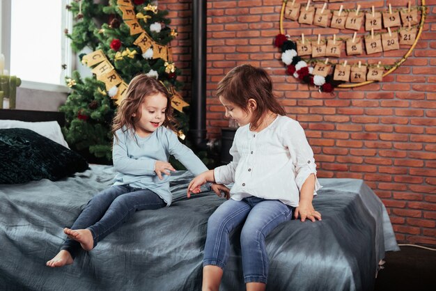 Passer du temps à jouer les uns avec les autres en attendant Noël. Les enfants sont assis sur le lit. Conception du nouvel an.