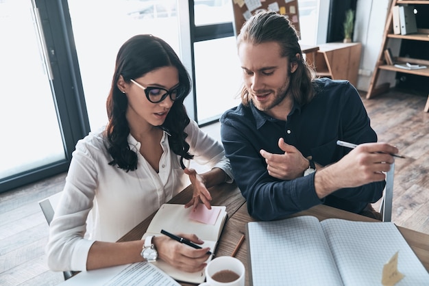 Passer en revue les détails. Vue de dessus de deux jeunes gens modernes en vêtements décontractés intelligents écrivant quelque chose