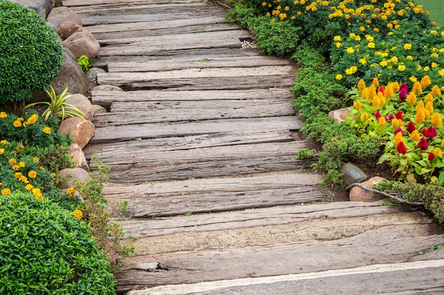 Passerelle en bois dans le jardin avec des feuilles vertes et de la pierre.