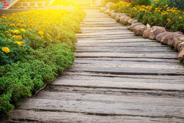 Passerelle en bois dans le jardin avec des feuilles vertes et de la pierre.