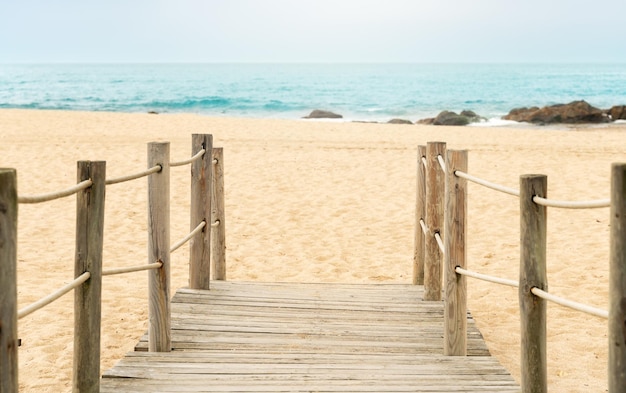 Passerelle en bois à l'entrée de la plage avec le bleu seaxDxA