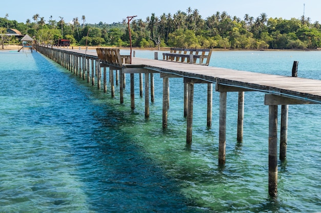 Passerelle en bois avec des sièges menant à la mer et à la plage en été.